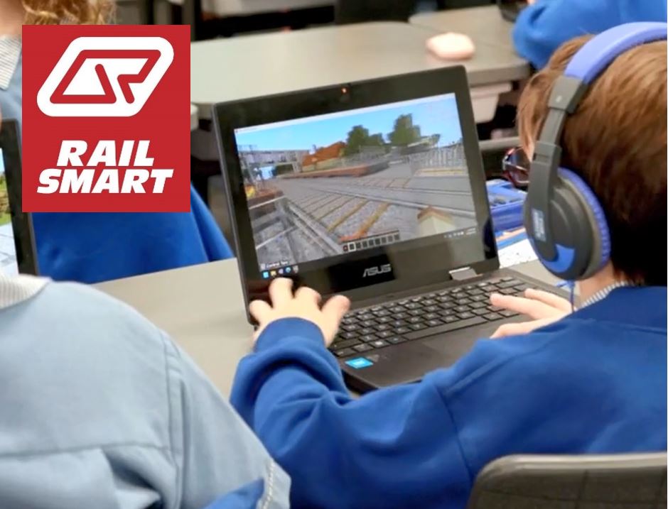 A screenshot from the Trck Stars! game. Several characters standing at a level crossing watching a Queensland Rail train pass by